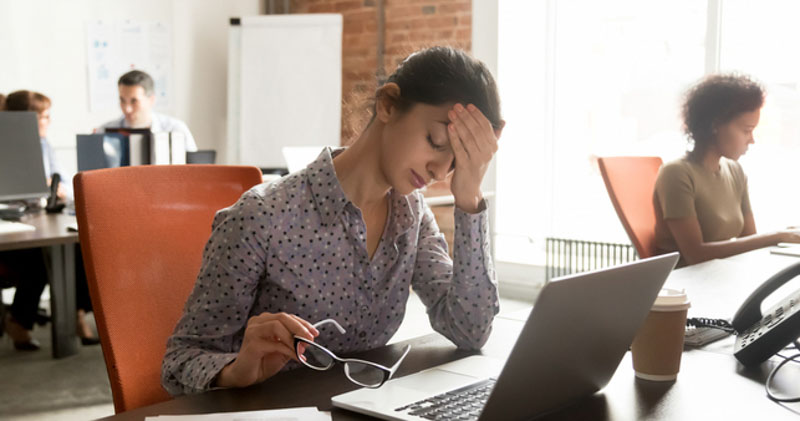 exhausted young female office worker flustered at desk