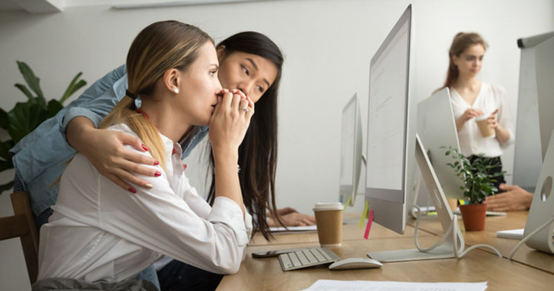 young female office worker consoles distraught female coworker at computer