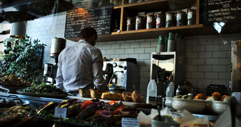 barista makes coffee and food in dark cafe kitchen