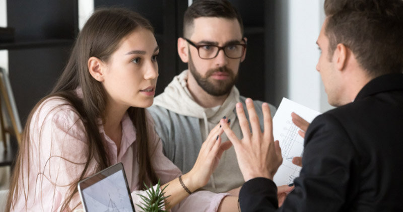 young frustrated couple argue with businessman