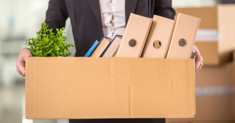 male office worker carrying belongings in cardboard box after dismissal