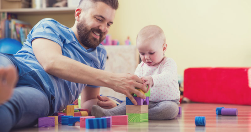 young father plays with baby in living room