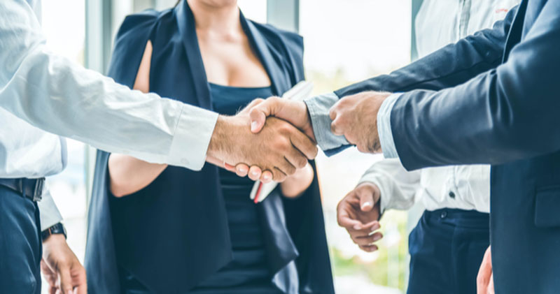 two male employees shake hands in corporate space