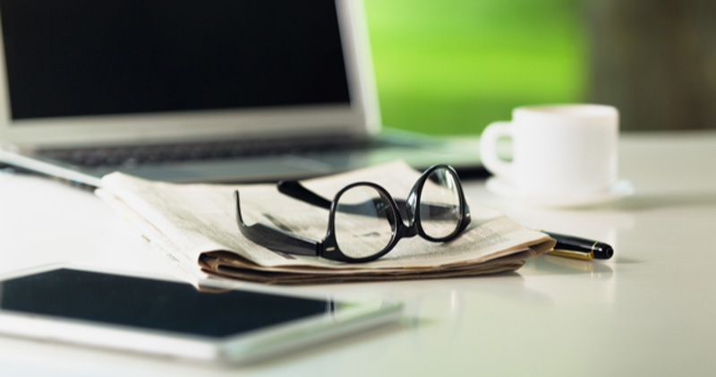 glasses sit on newspaper on working desk