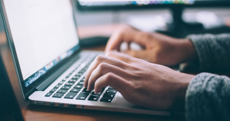 male hands typing on laptop