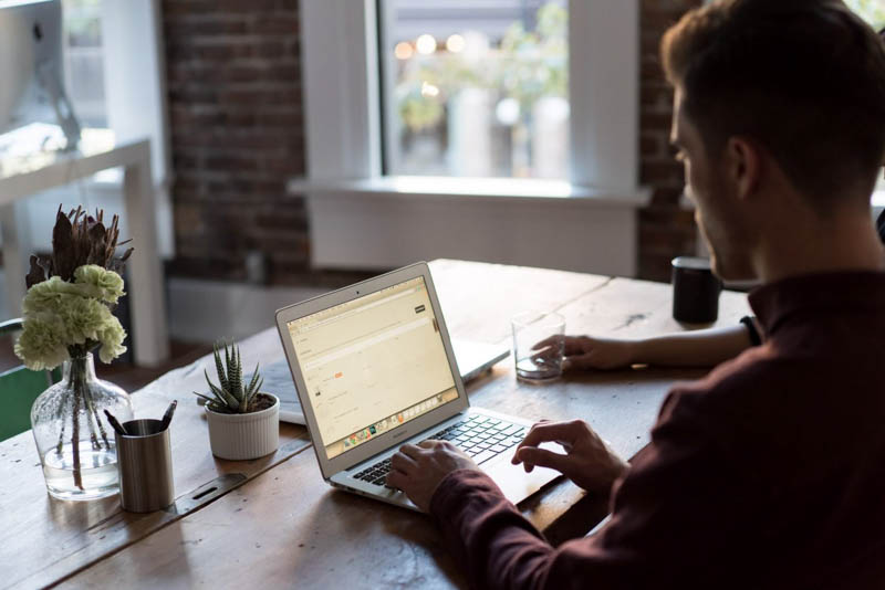 man works at laptop in dark timber office space