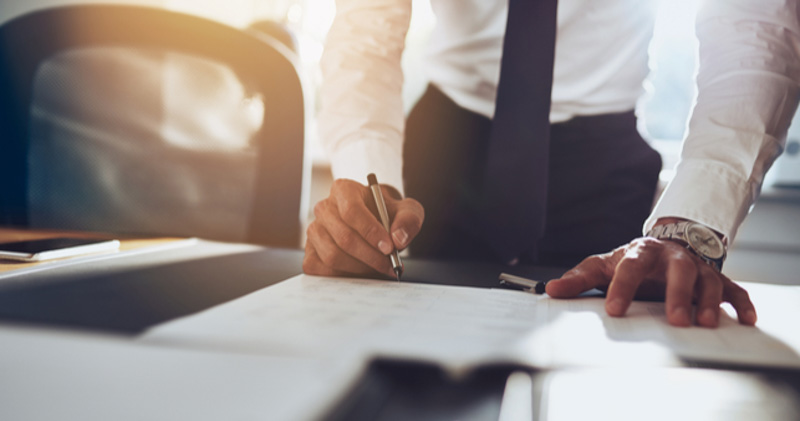 male corporate employee fills out contract on table