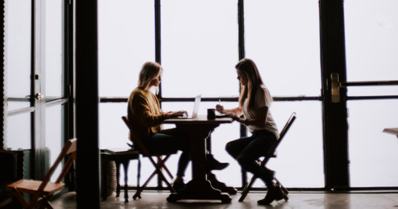 two female employees have work meeting in dark cafe