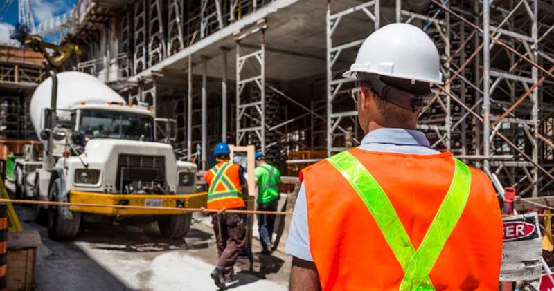 construction worker examines cement truck on building site