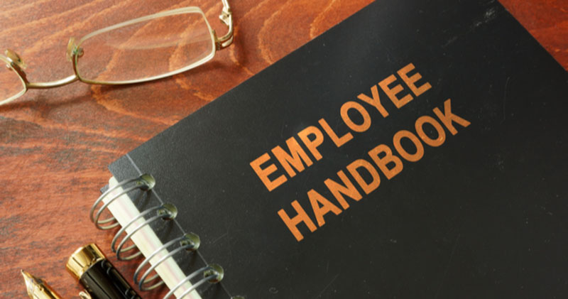 black employee handbook on wooden table