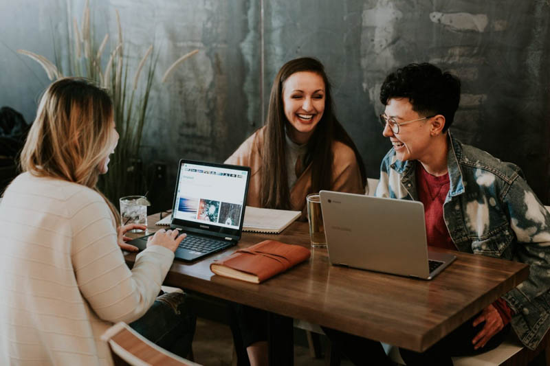 cheerful young media workers catch up for cafe meeting