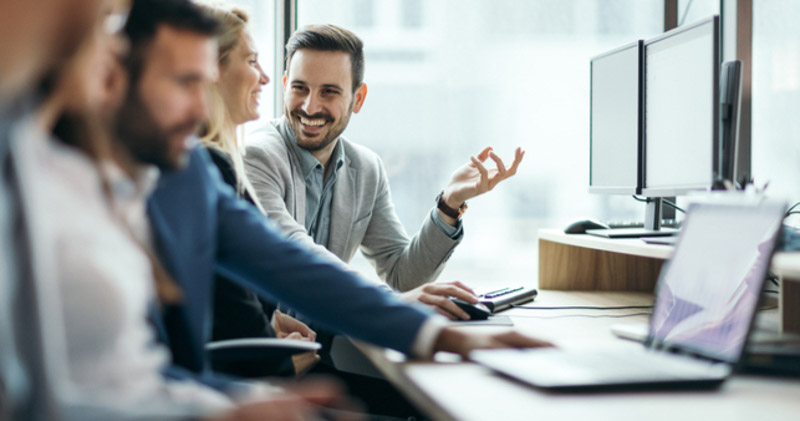 amused coworkers sit at desk in corporate space