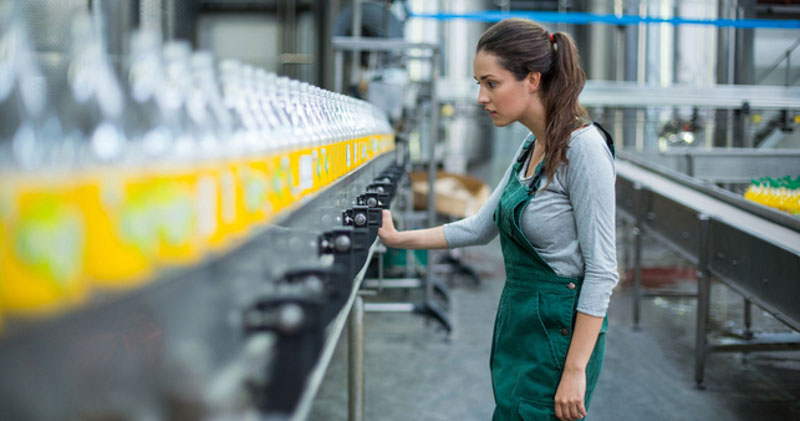 female factory worker examines bottles