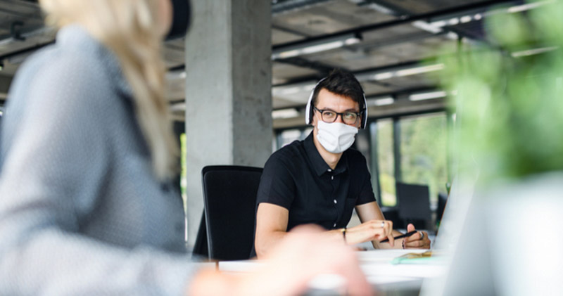 masked male employee in corporate space