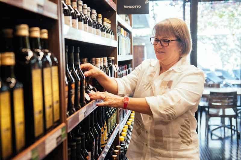 female business owner tending to olive oil on shelf