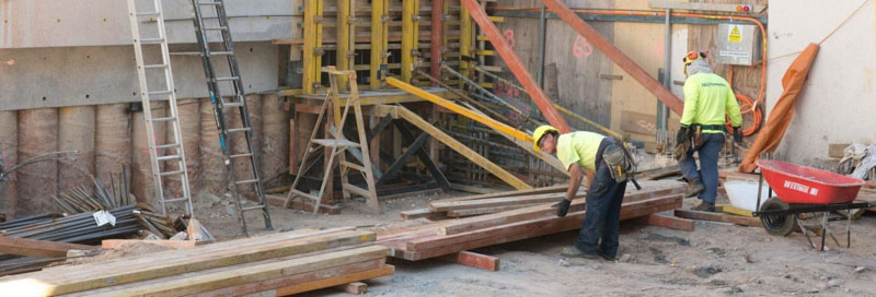 2 construction workers lift timber on worksite