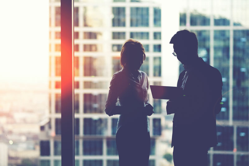 corporate coworkers examine chart by window