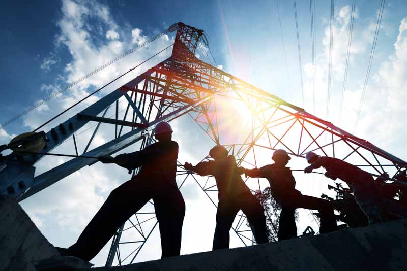 construction workers pull on rope near tower