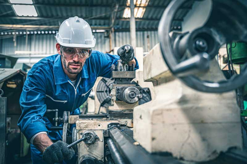 factory worker in blue jumpsuit works on machine