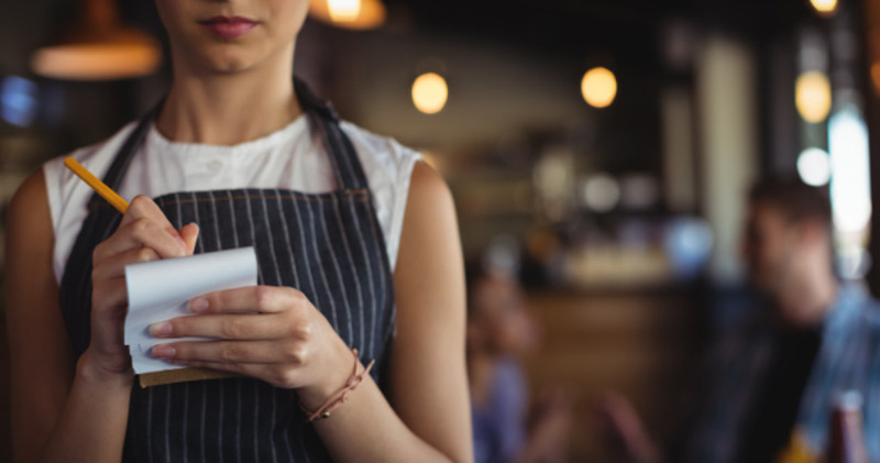 waitress stands with notepad writing order