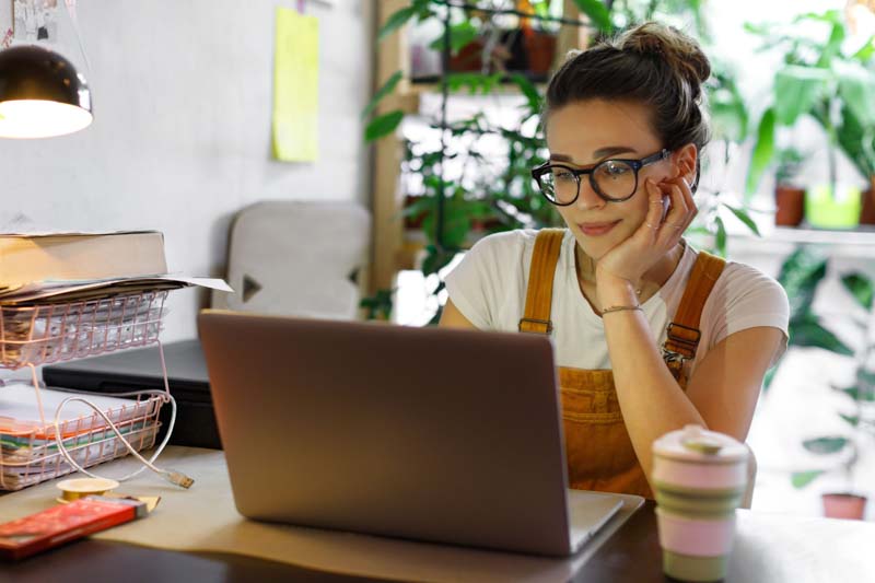 female remote worker reads emails in plant filled office