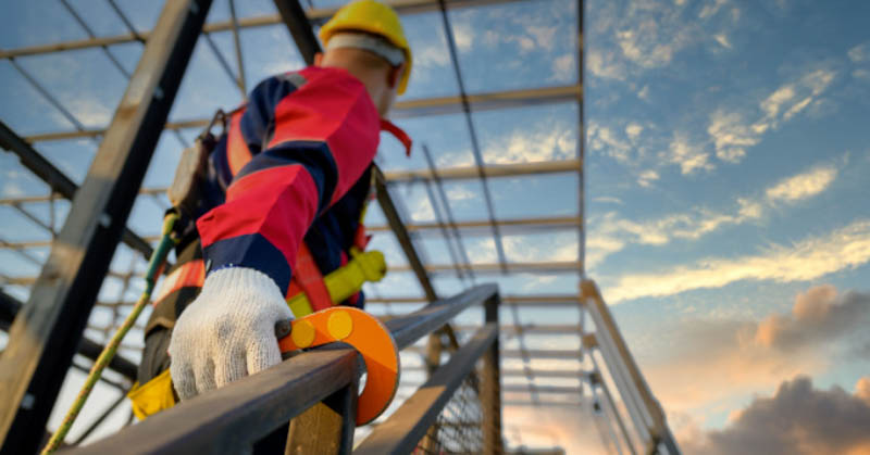 construction worker fasten safety harness to railing