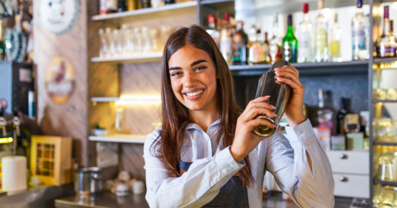 female bartender shakes cocktail shaker
