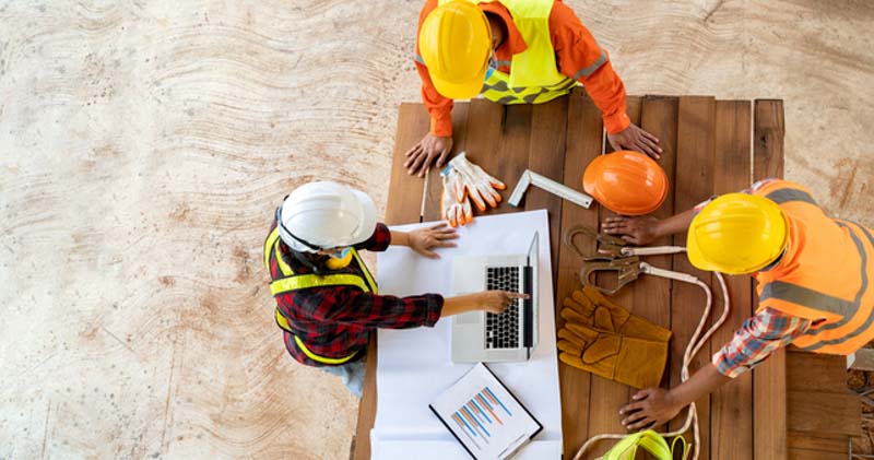 construction workers look at plans on bench