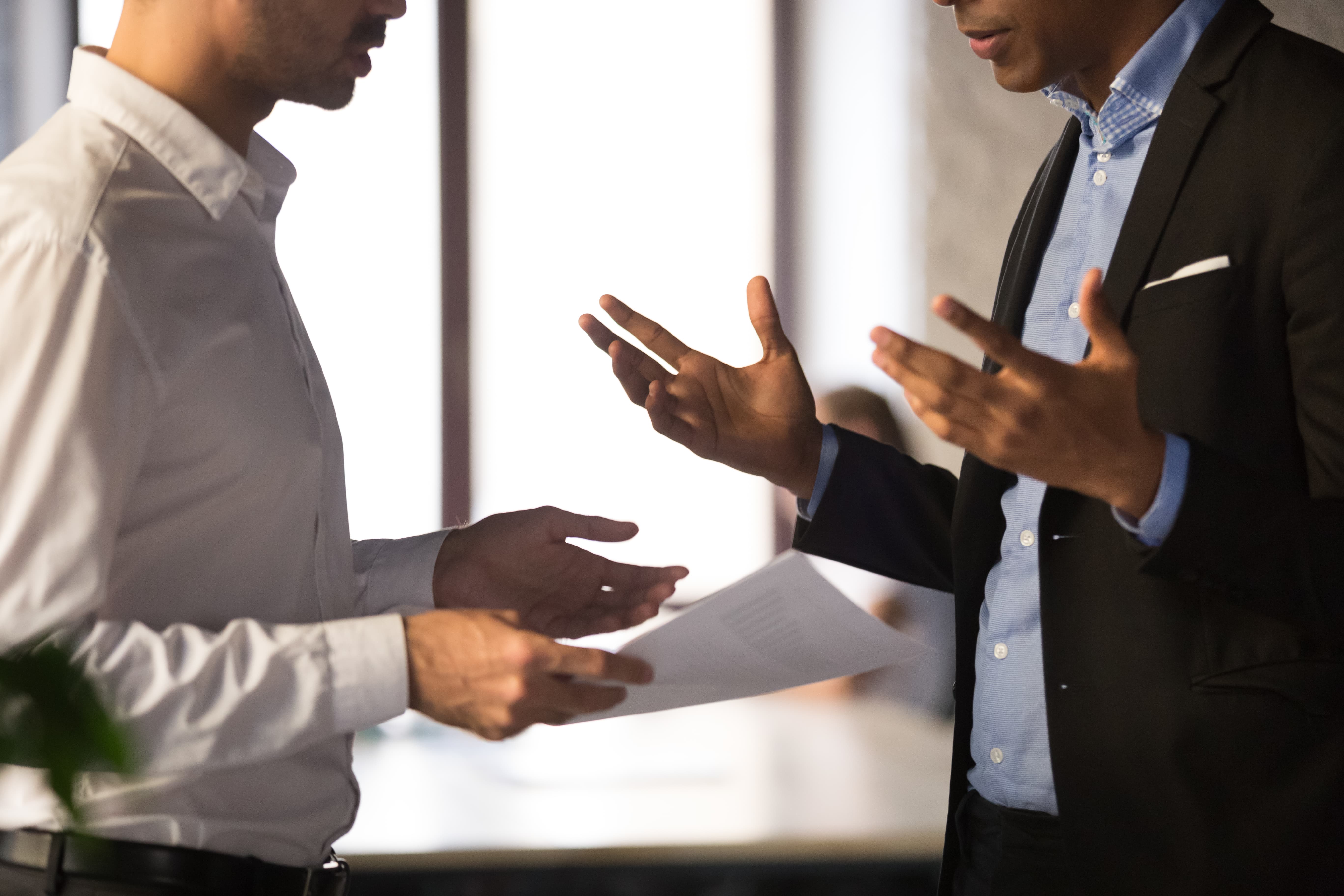 Two faceless men discussing paperwork