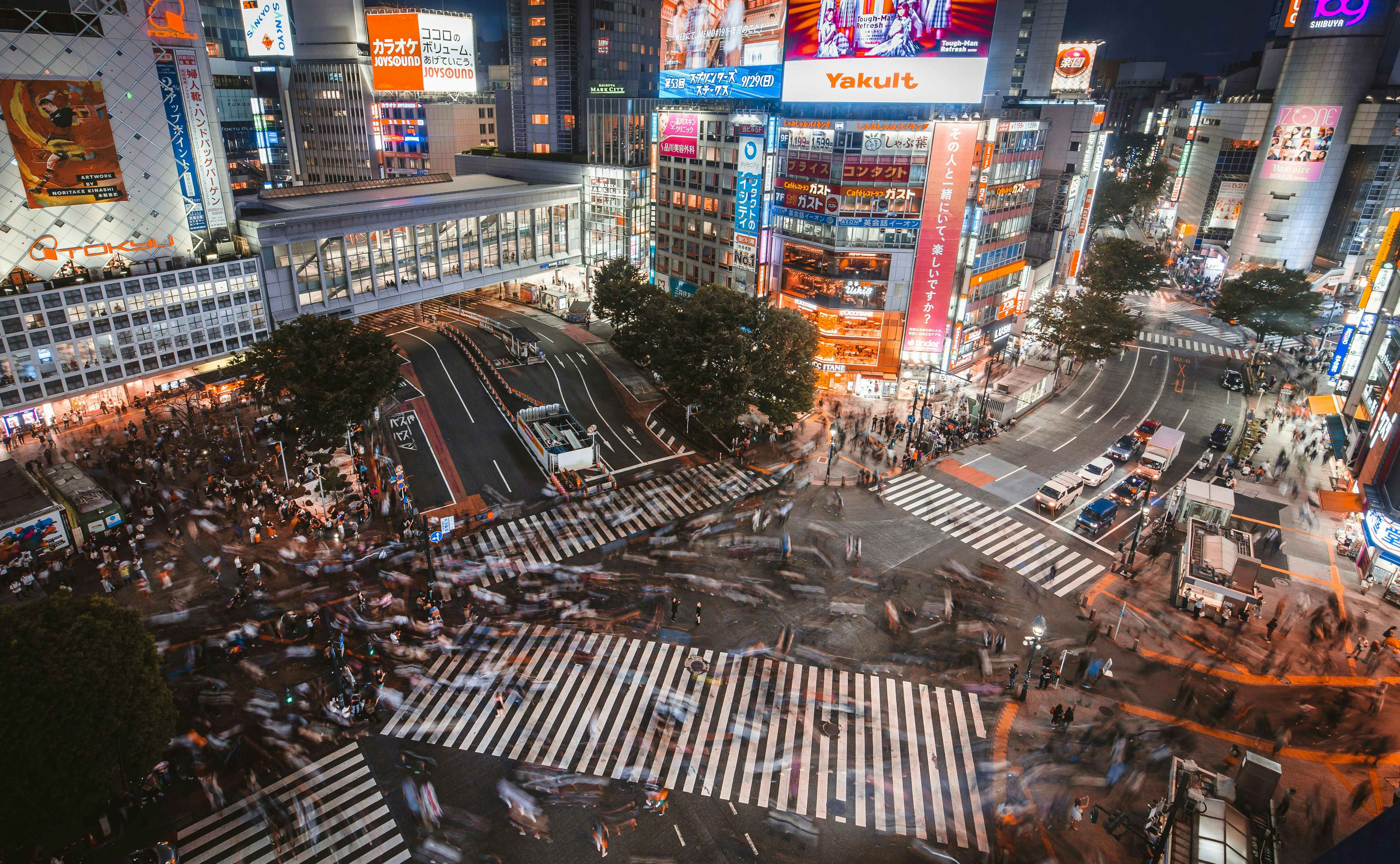 Shibuya, Tokio Cruce de Shibuya de noche, con cientos de peatones y grandes pantallas luminosas.