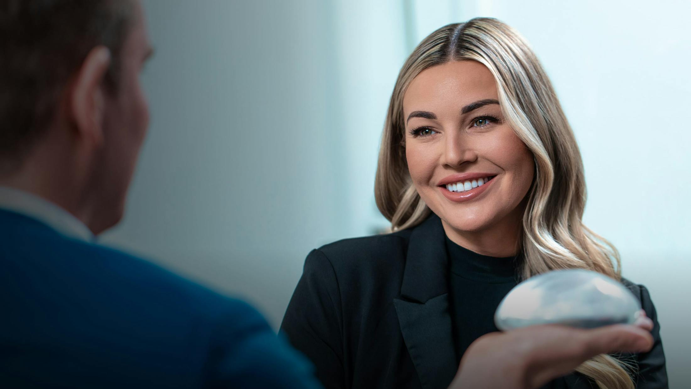 Dr. Gardenier speaking with a female patient while holding a breast implant