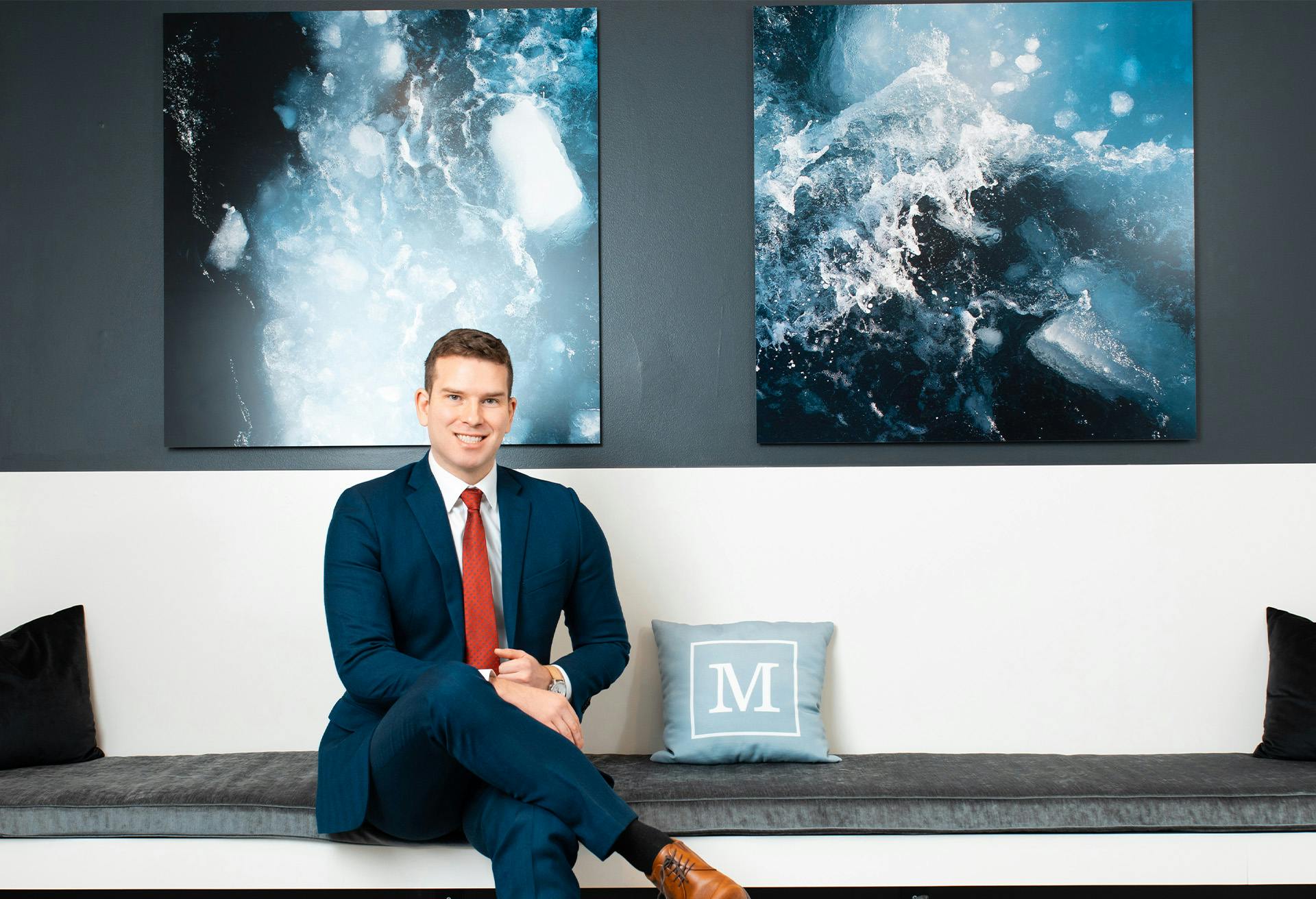 Dr. Gardenier sitting on a bench in front of artwork