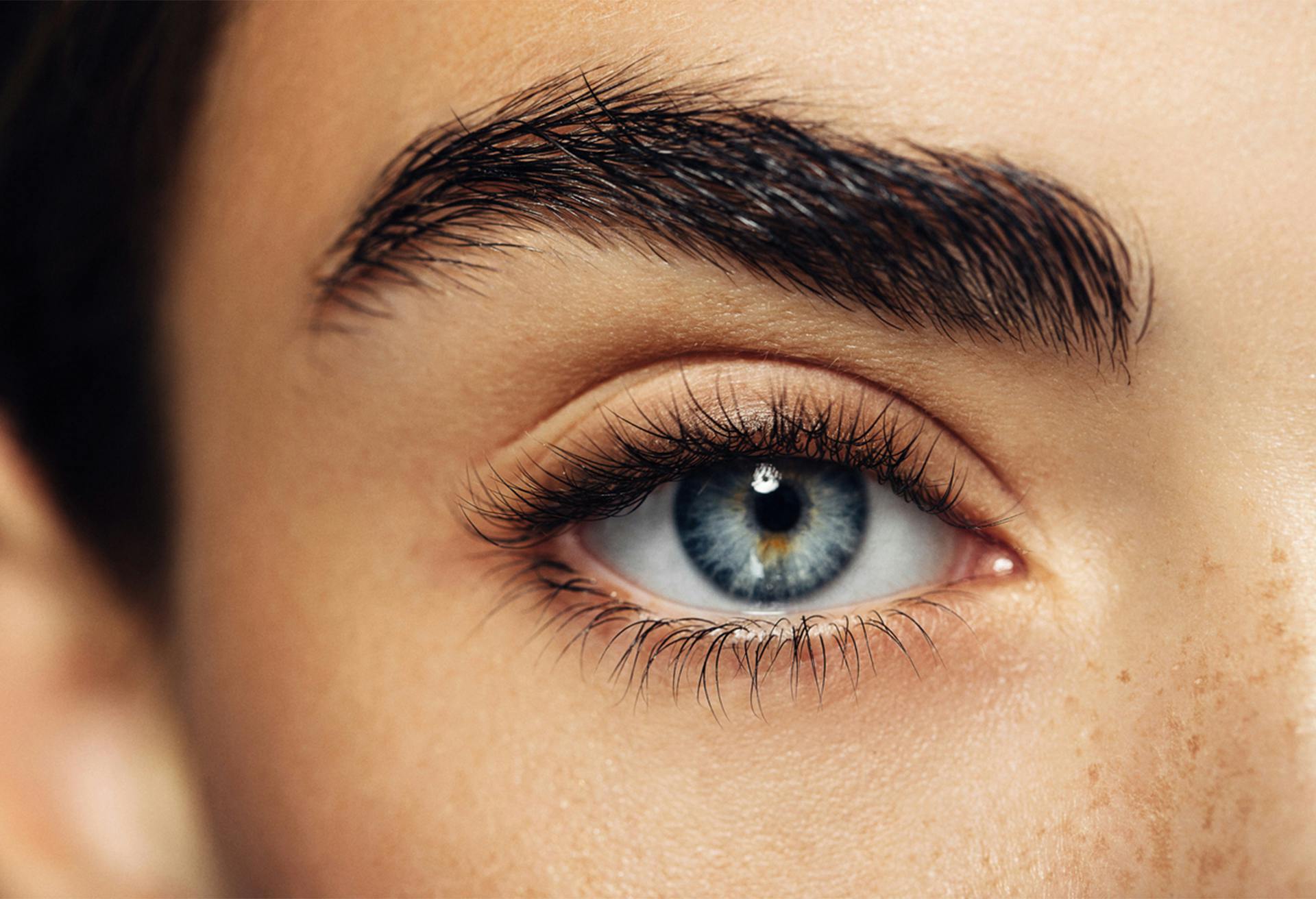 Woman's blue eye with thick dark eyebrow