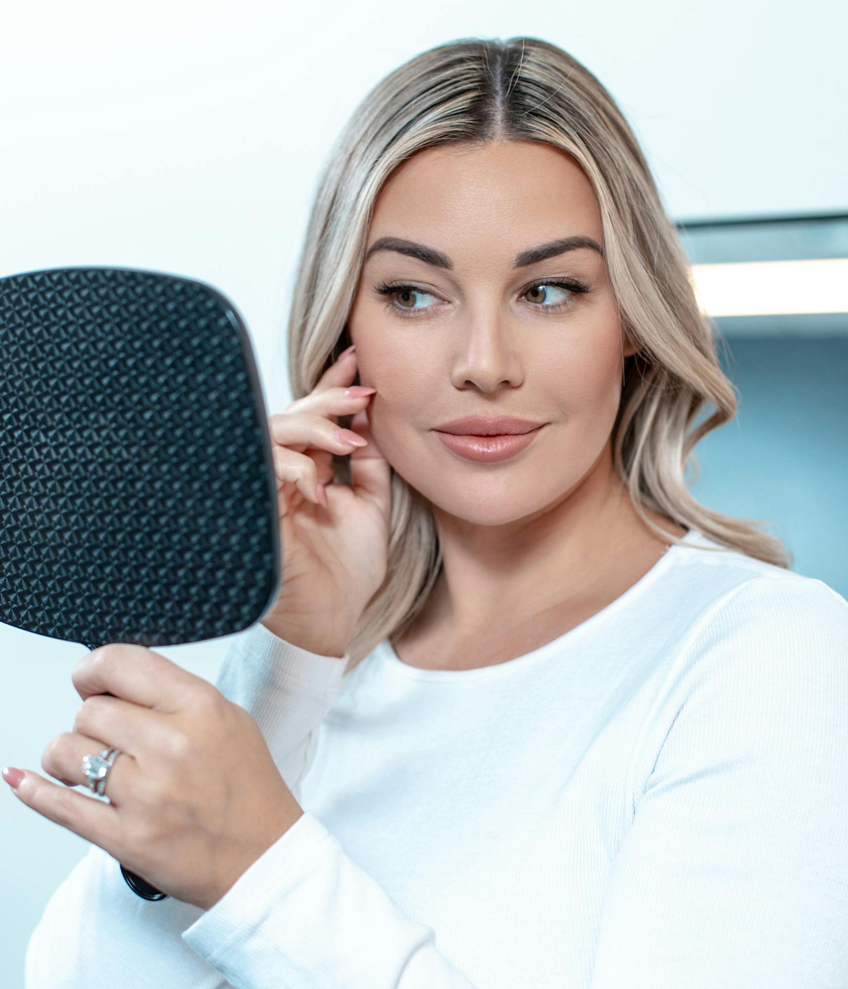 blonde woman holding a mirror