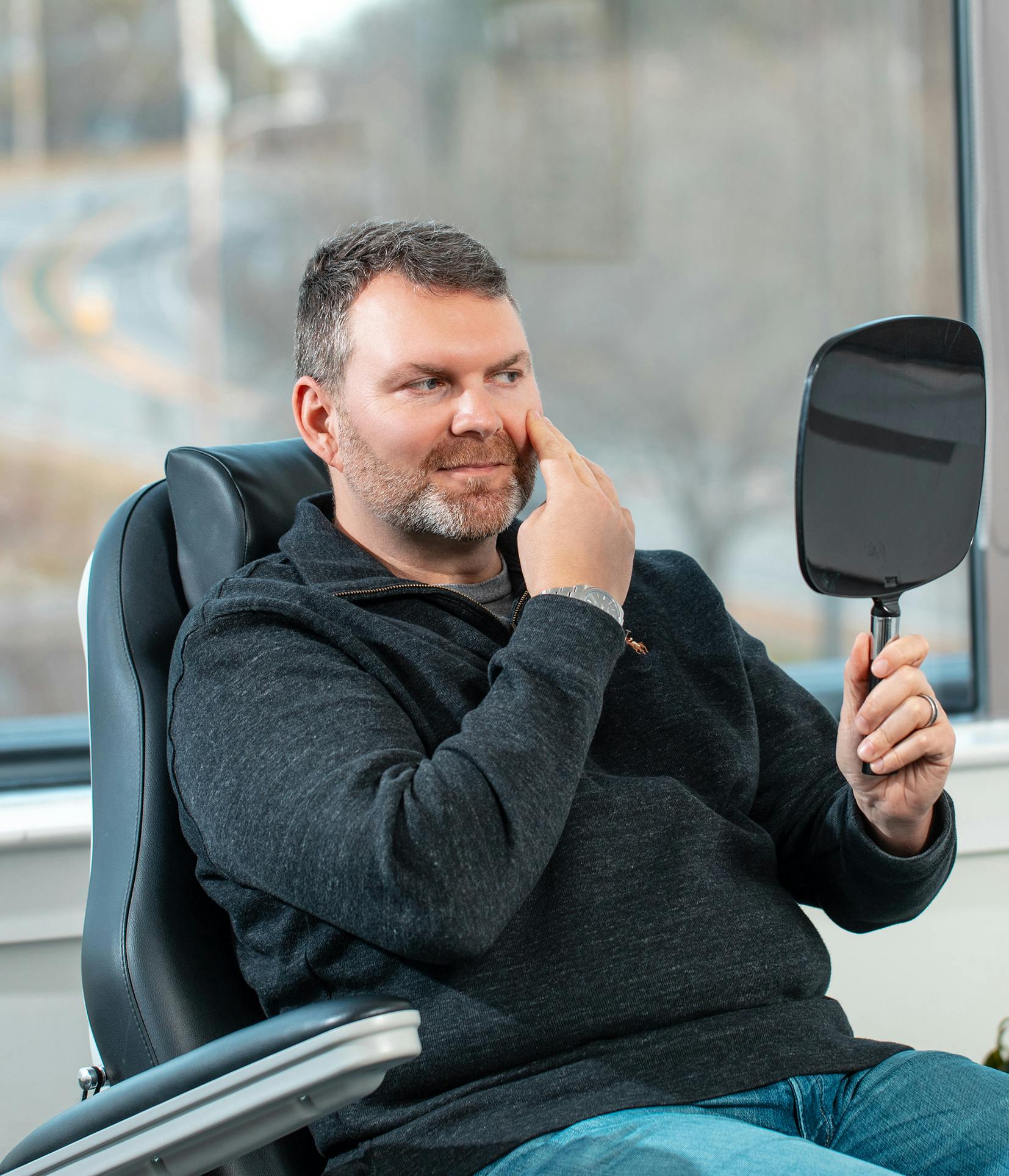 man sitting in a chair holding a mirror