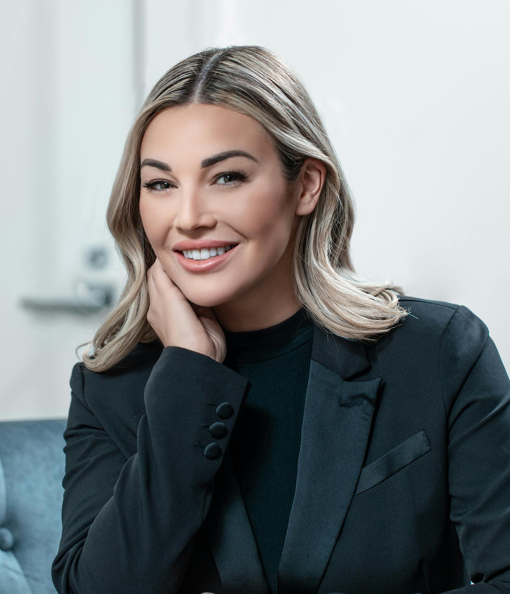 smiling woman in black suit sitting on a blue couch