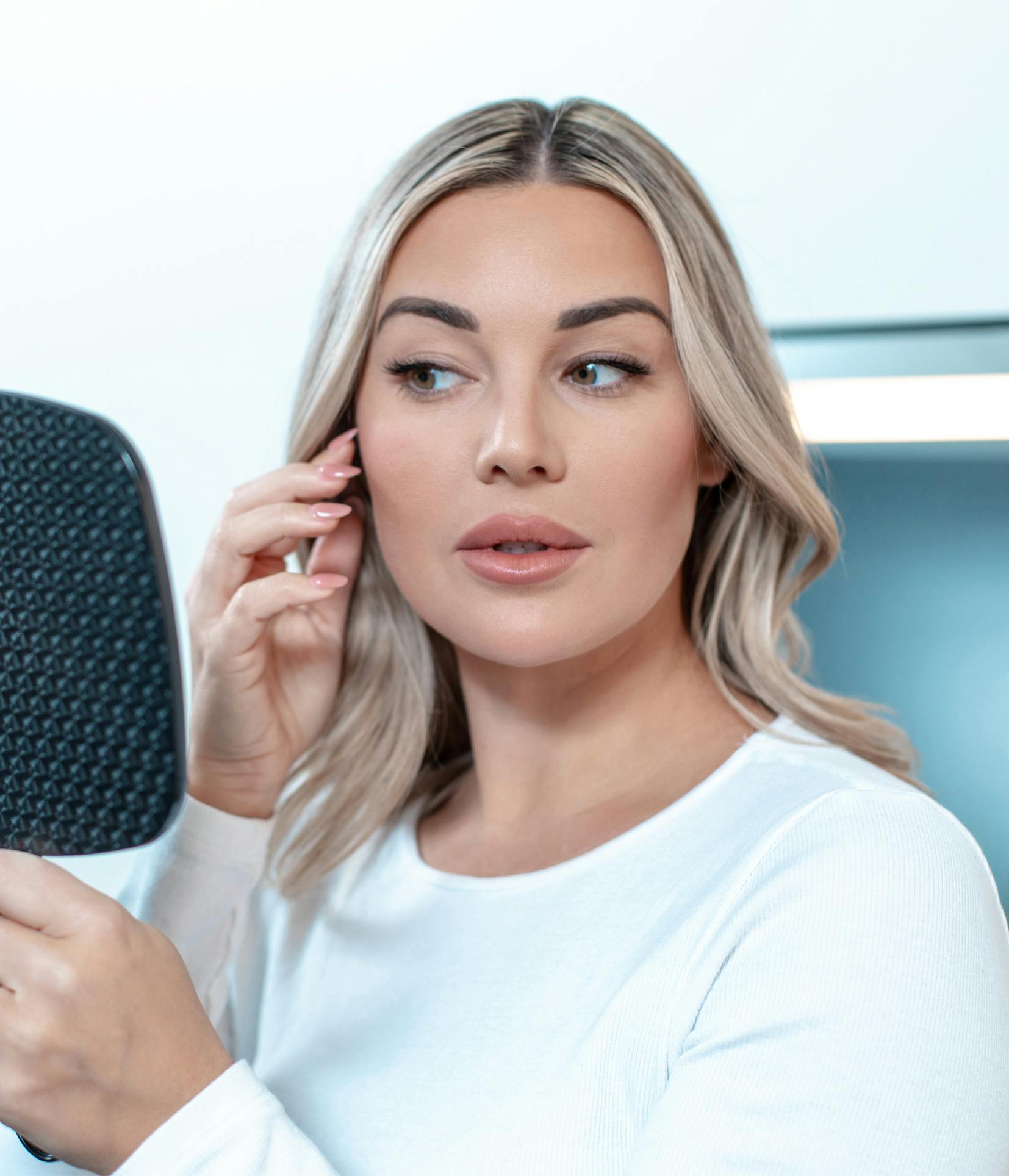 blonde woman holding a mirror