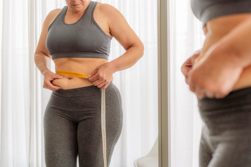 woman measuring her stomach in the mirror