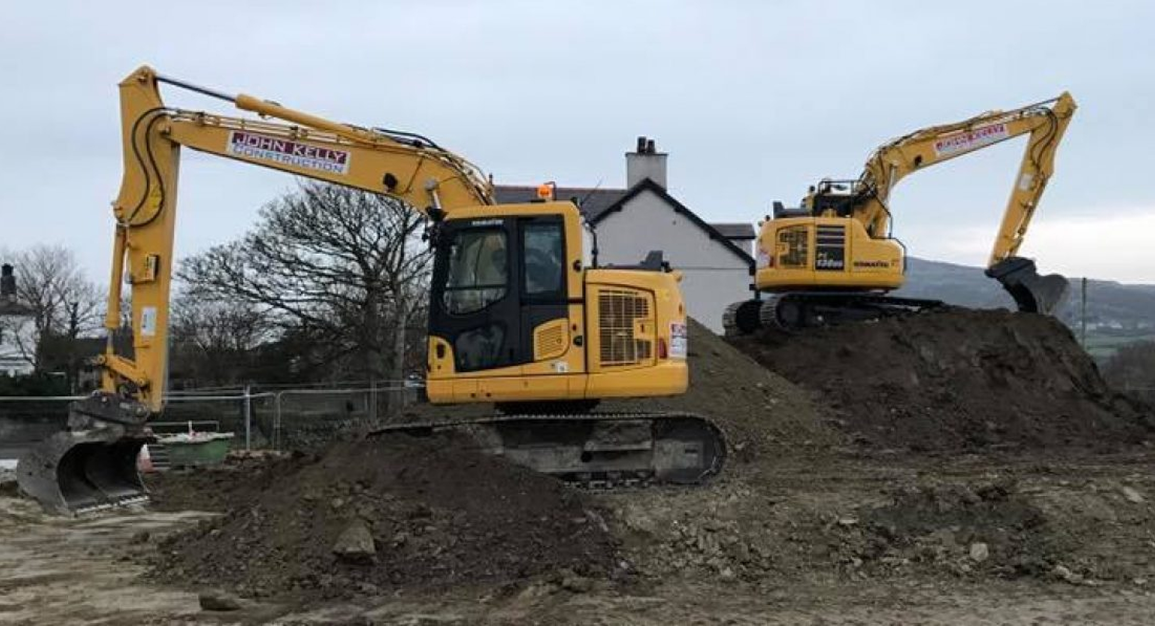 Two yellow diggers on muddy worksite