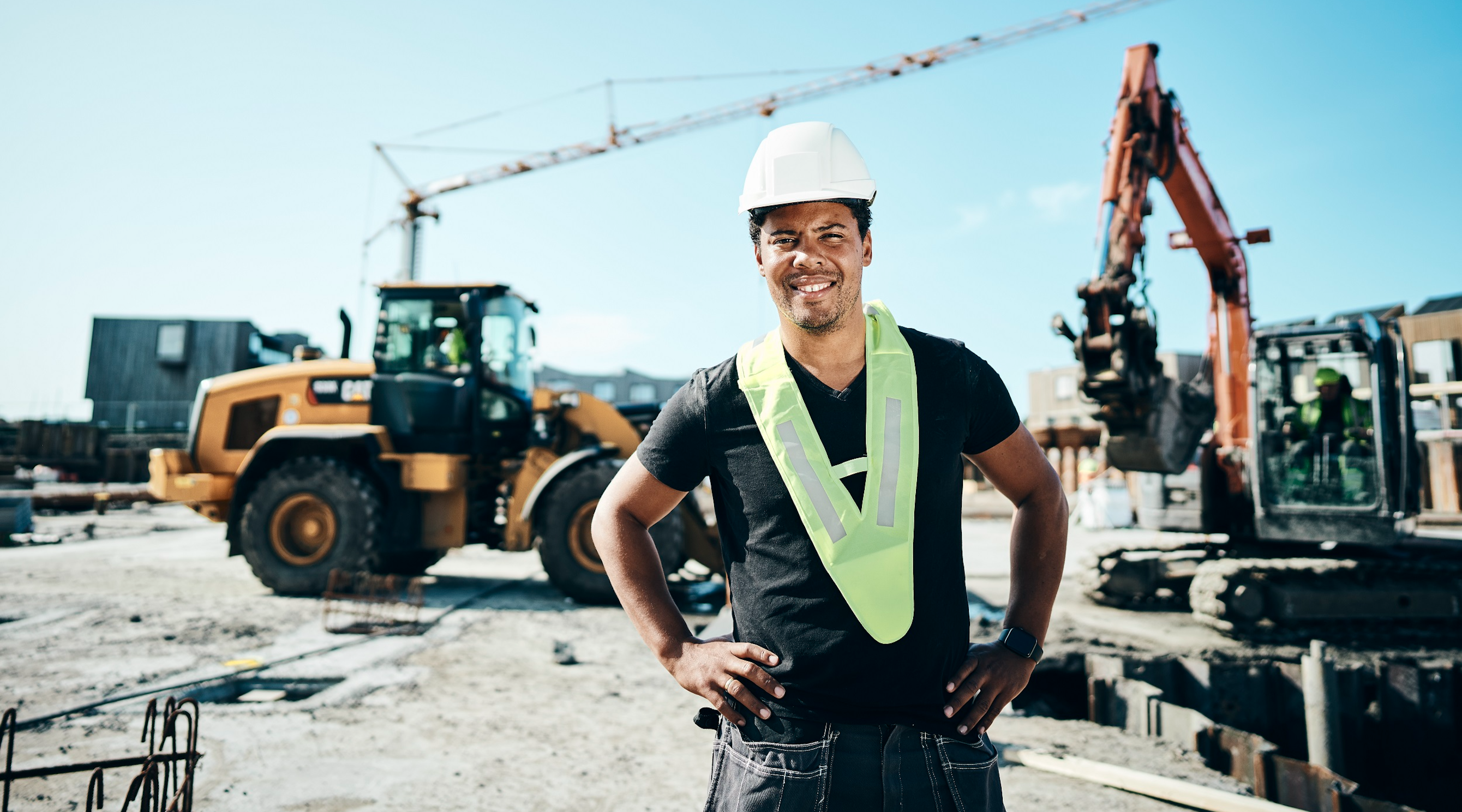 Construction worker in hard hat and high vis standing in front of machinery on a construction site