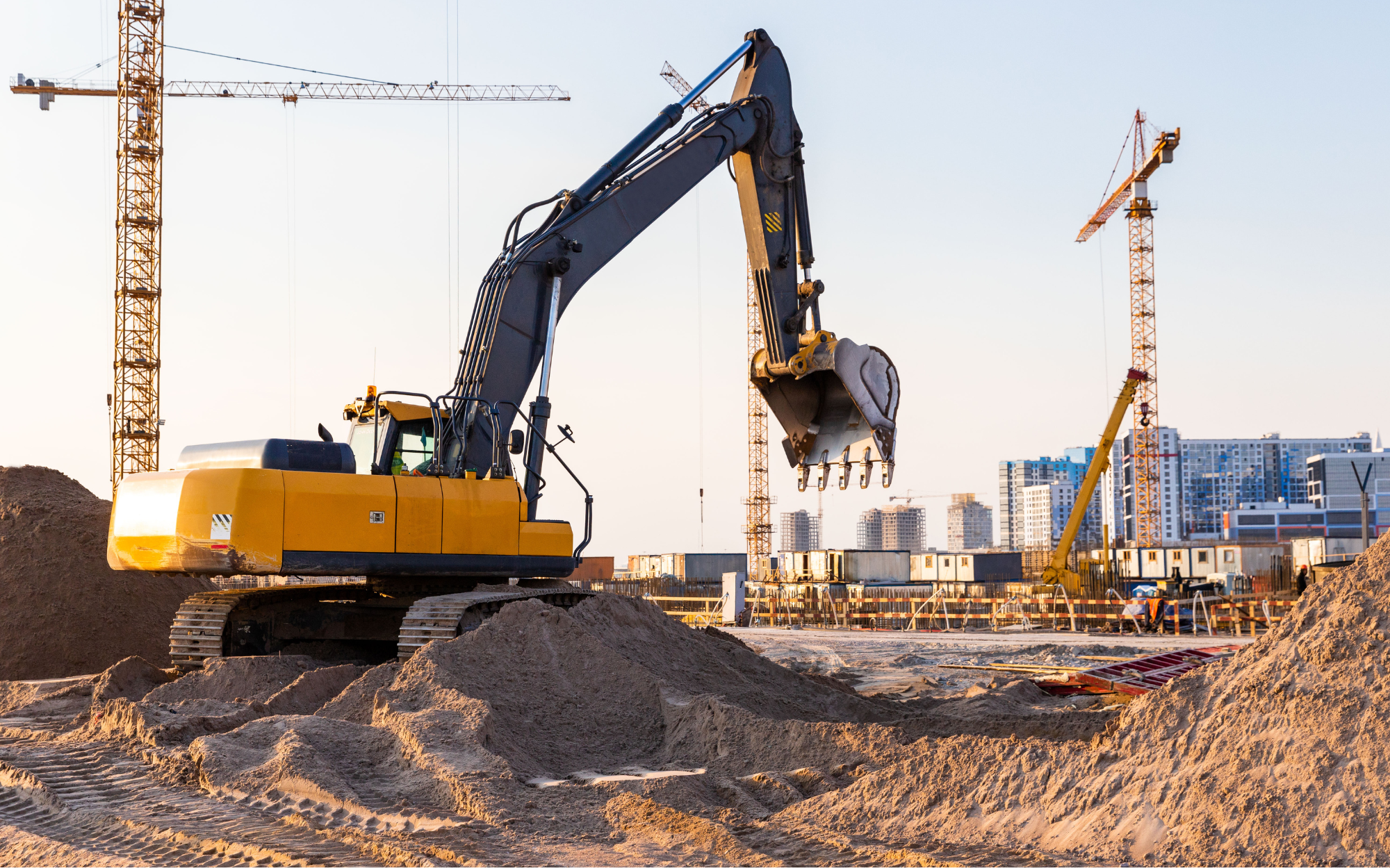 Construction site with digger and buildings in the background