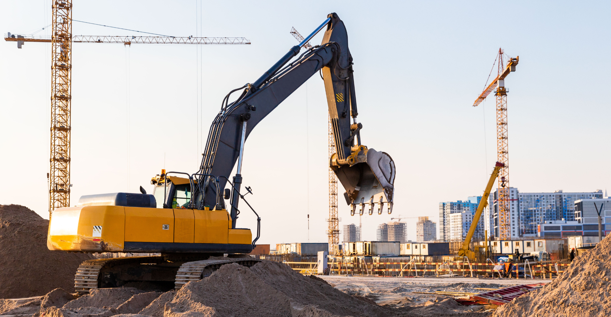 Construction site with digger and buildings in the background