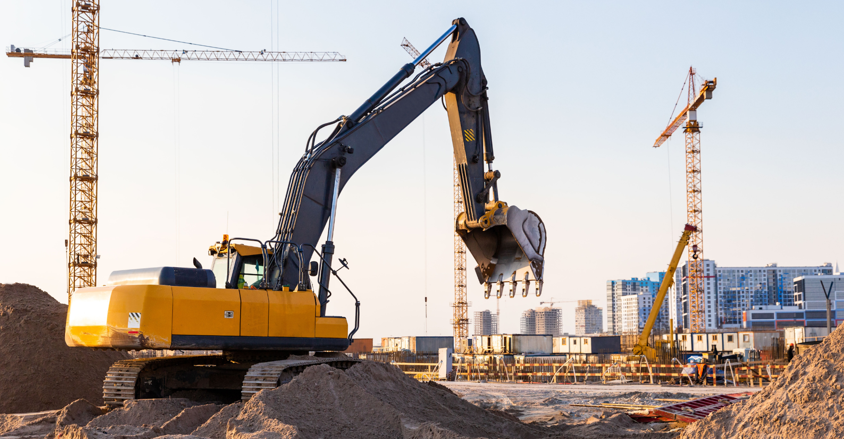 Bouwplaats met graafmachine en gebouwen op de achtergrond