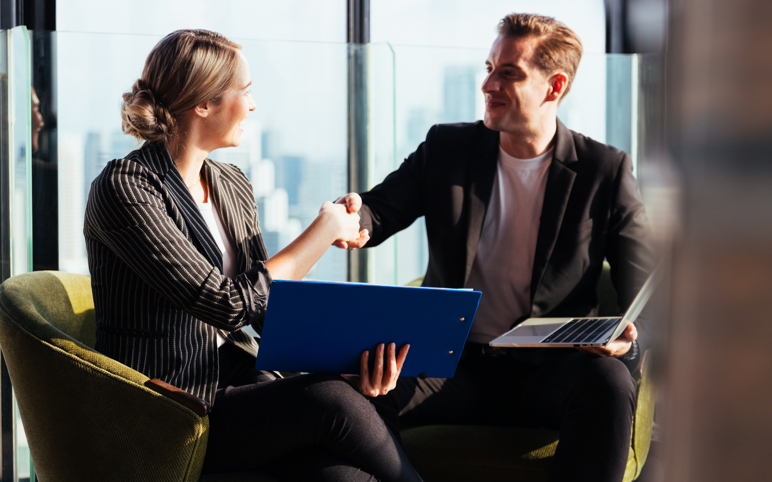 Woman in blazer shaking hands with man in suit