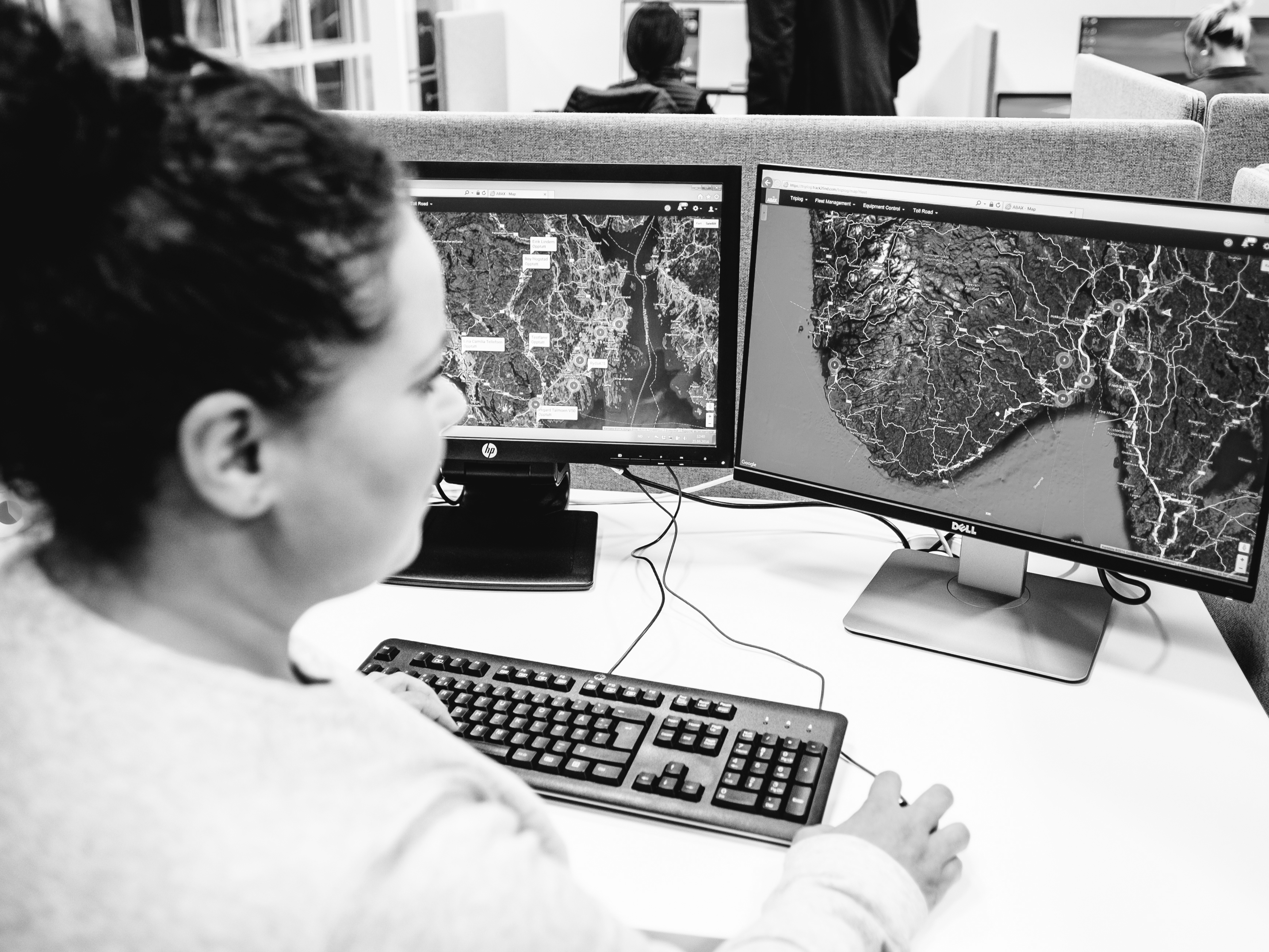 Woman looking at computer screen which shows a map in black and white
