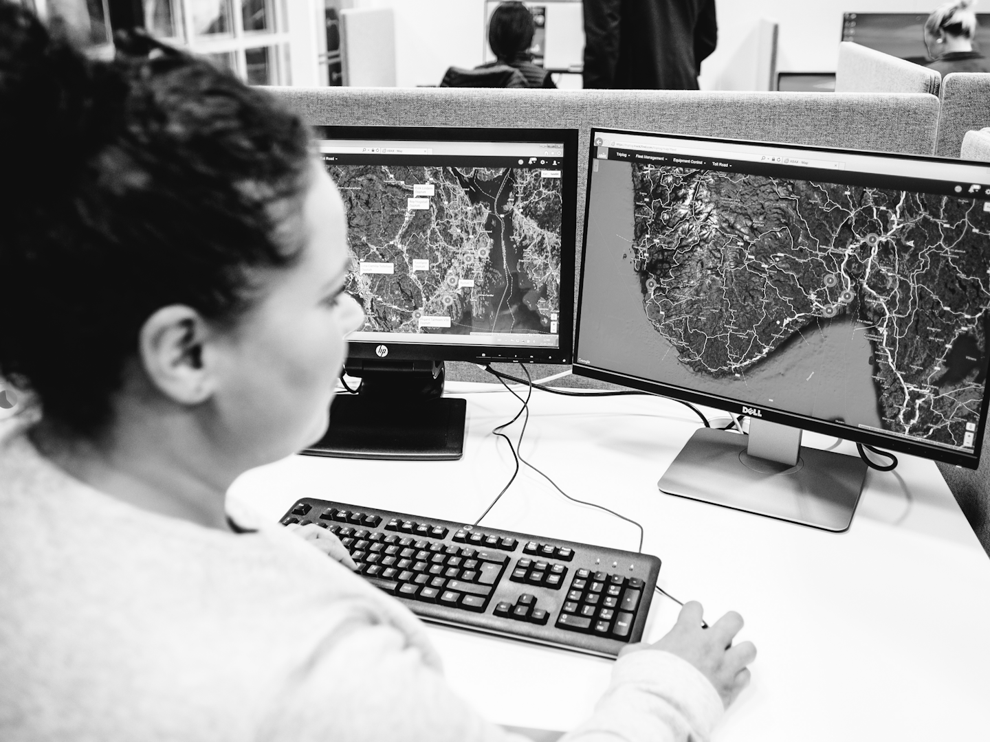 Woman looking at computer screen which shows a map in black and white