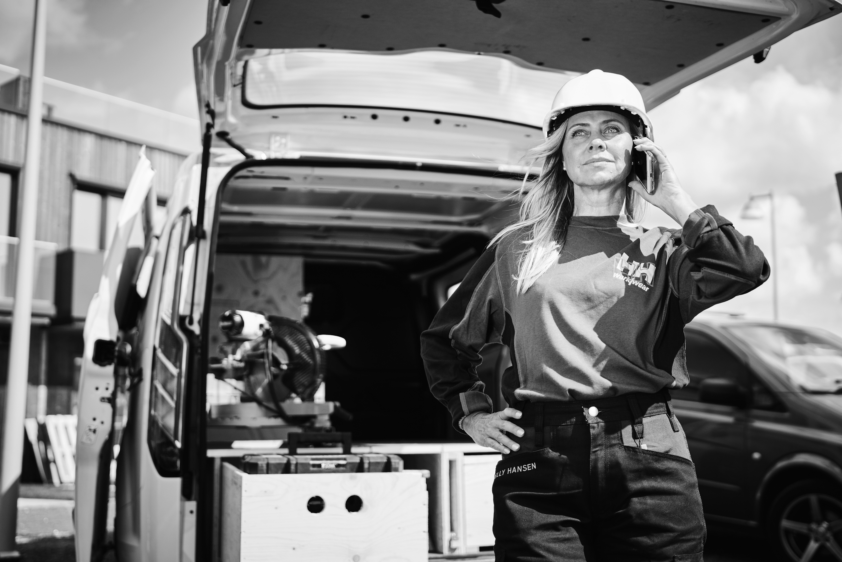 Worker woman talking on the phone in front of a van black and white