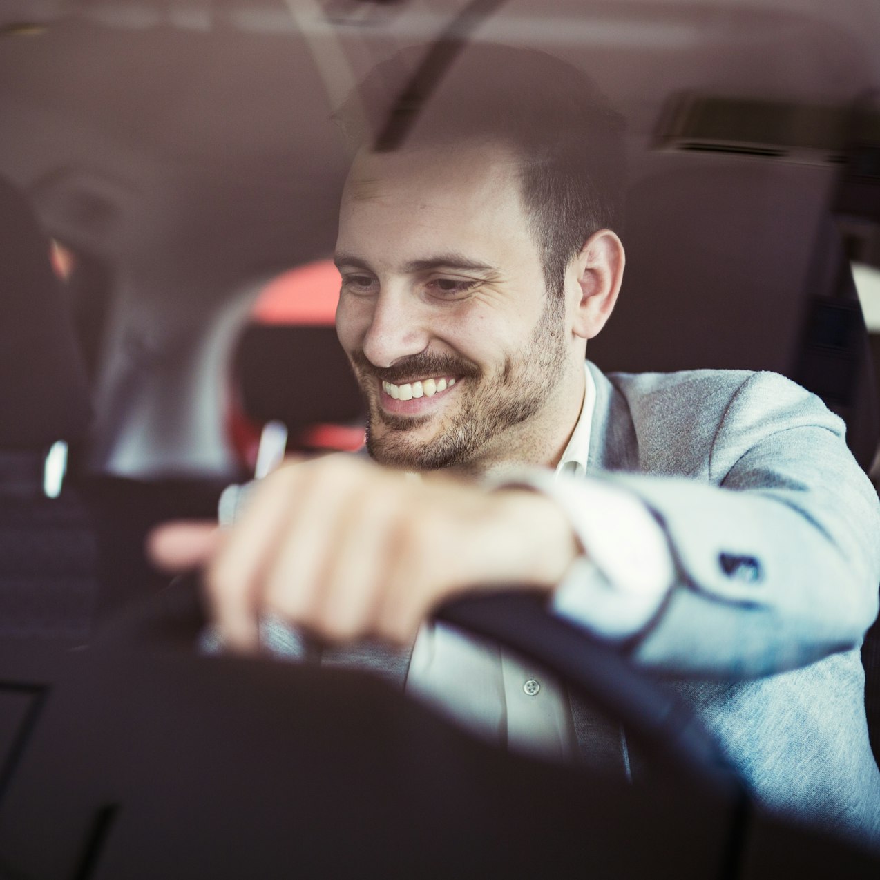 Man in car smiling with hand on stearing wheel