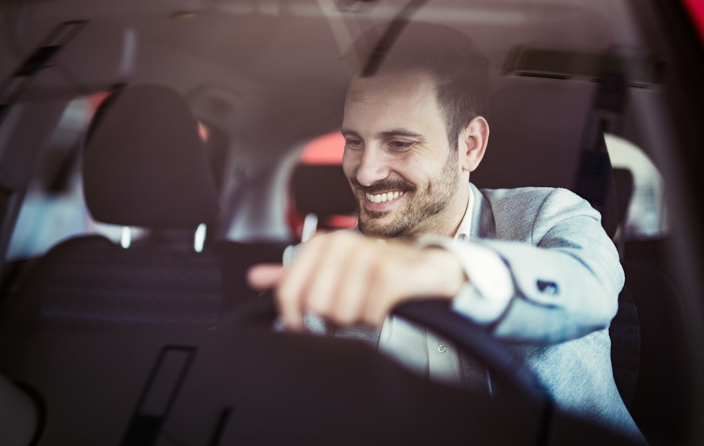 Man in car smiling with hand on stearing wheel