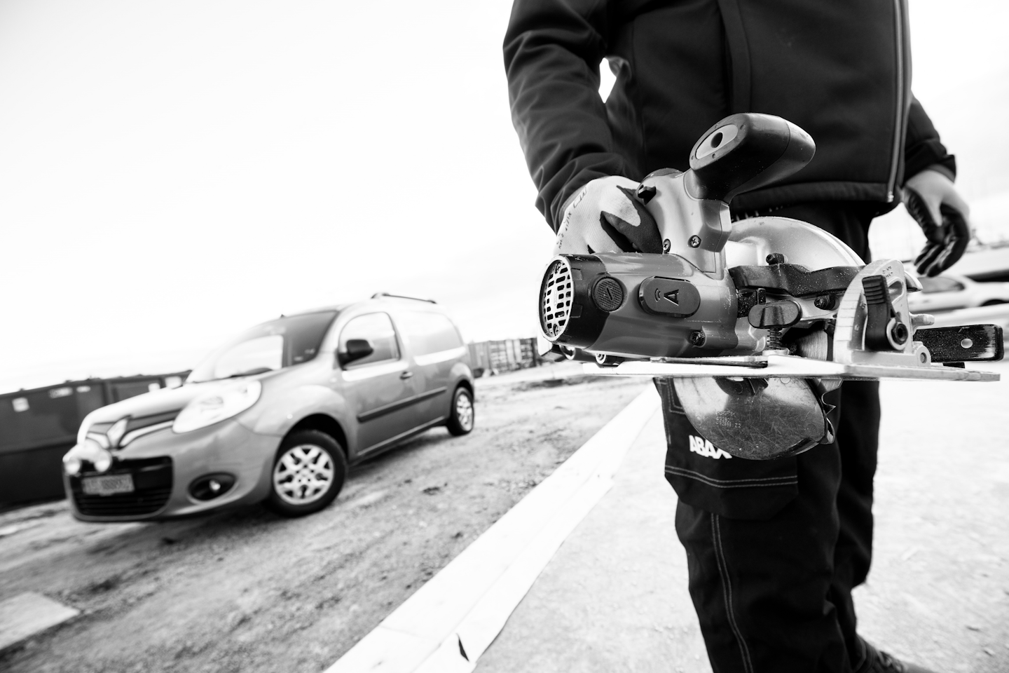 Man holding a tool with tracking unit on with work van in the background black and white